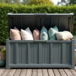 Coffre de jardin en résine ouvert sur une terrasse en bois avec des outils et coussins rangés à l'intérieur