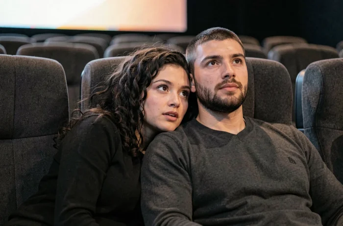 Couple ému regardant un film au cinéma dans des fauteuils inclinables modernes