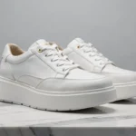 Baskets compensées de luxe Serafini en cuir blanc sur marbre de Carrare, détails couture et semelle épaisse sculptée